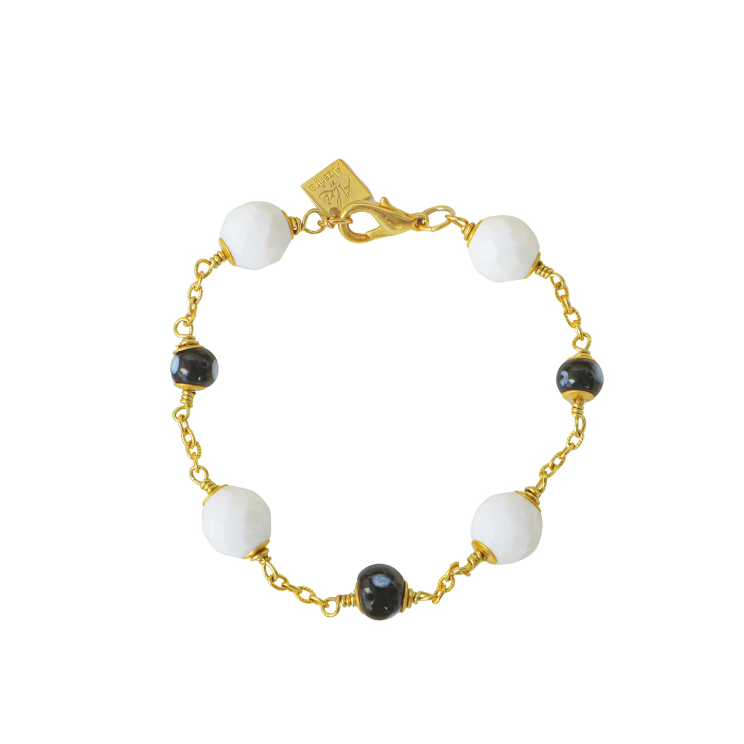 Bracelet with white and black beads on a gold chain against a white background