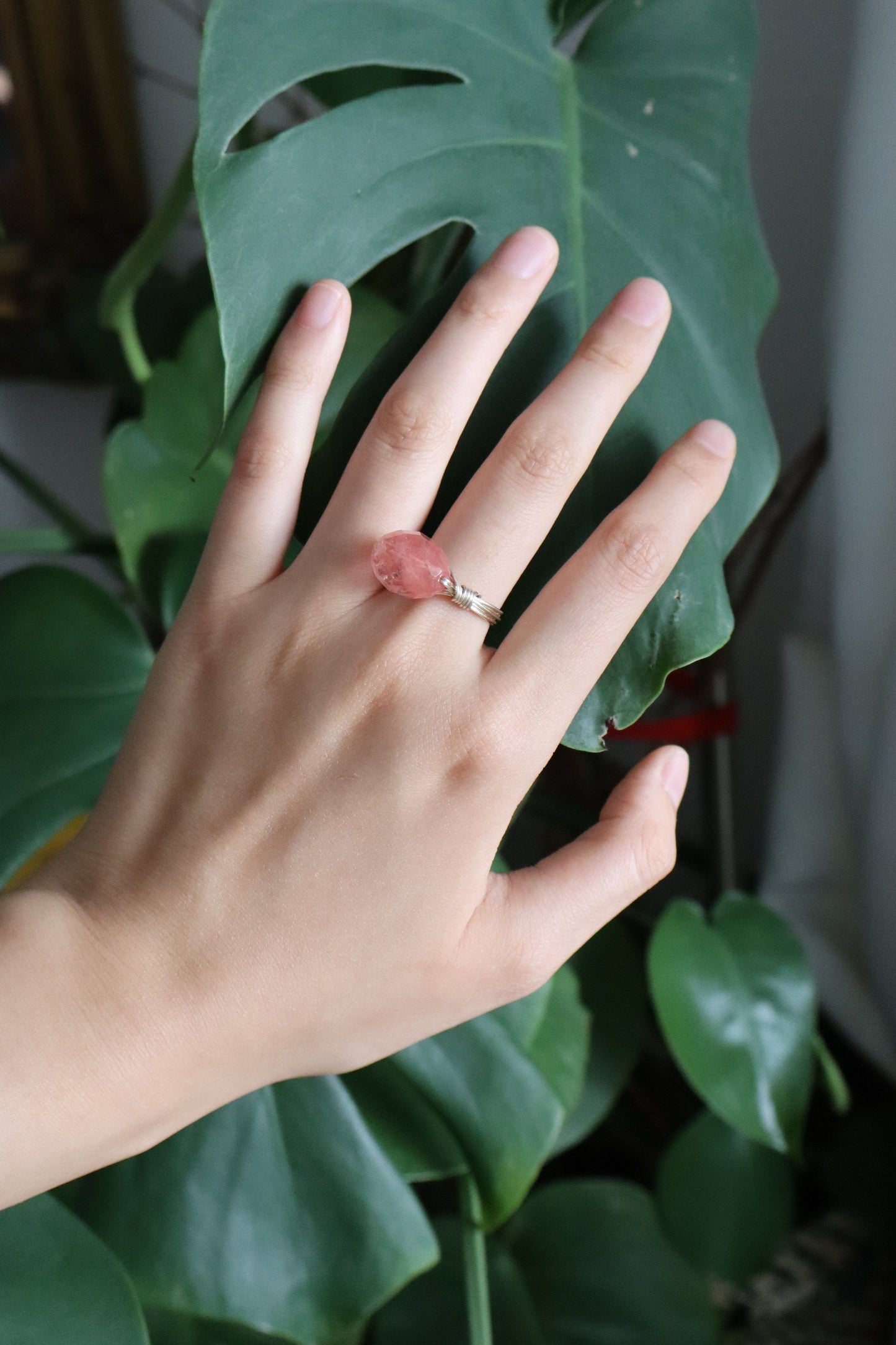 Hand with a pink ring on a leafy green plant