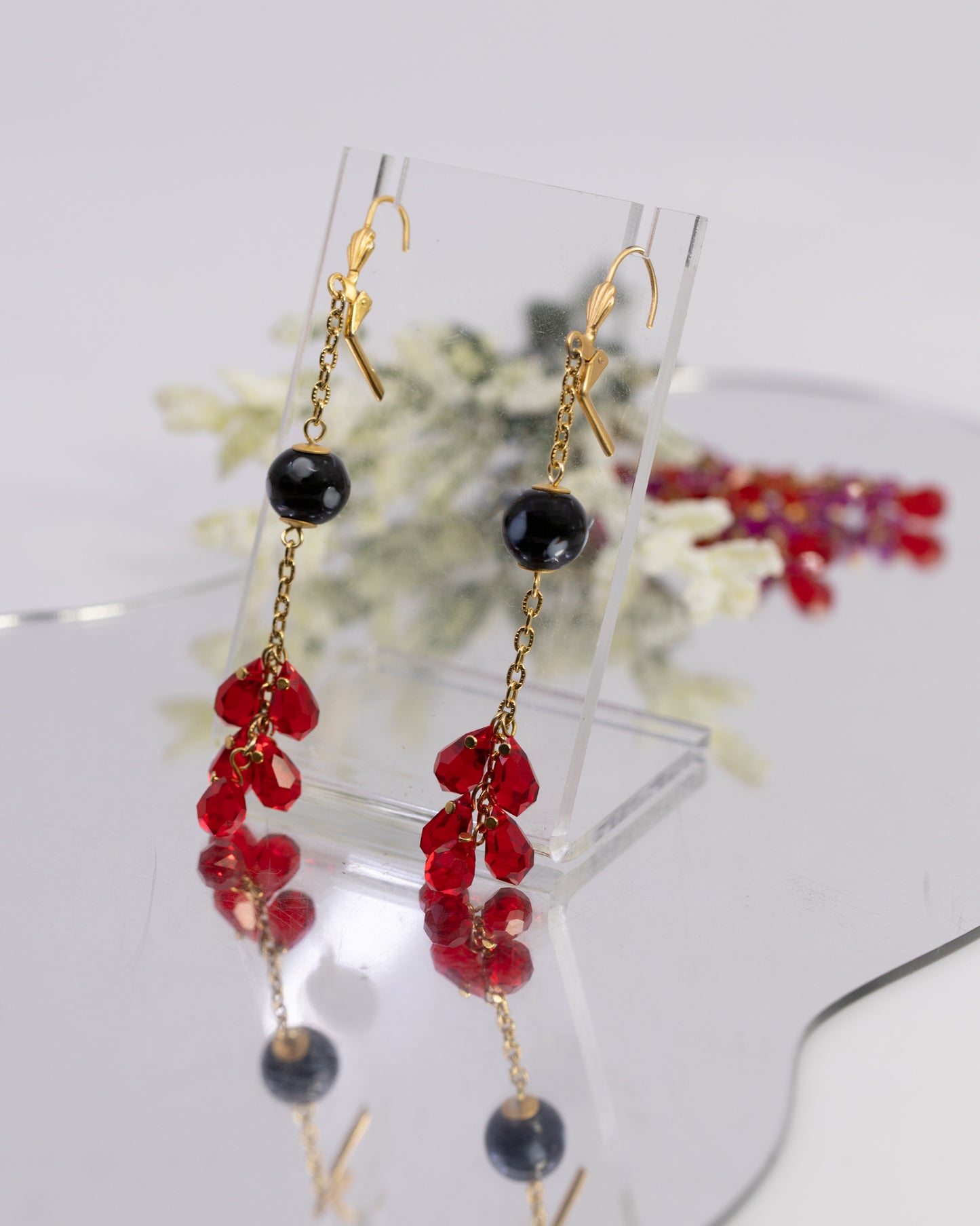 Pair of earrings with red and black beads on a white background