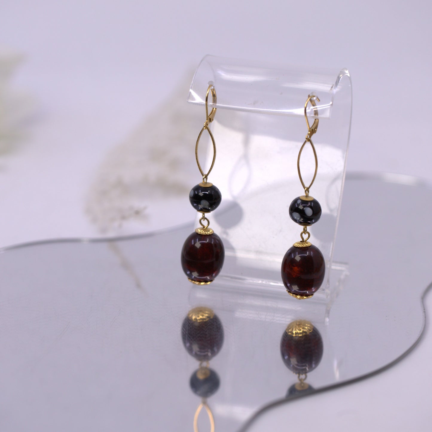 Pair of beaded earrings on a clear stand against a light background