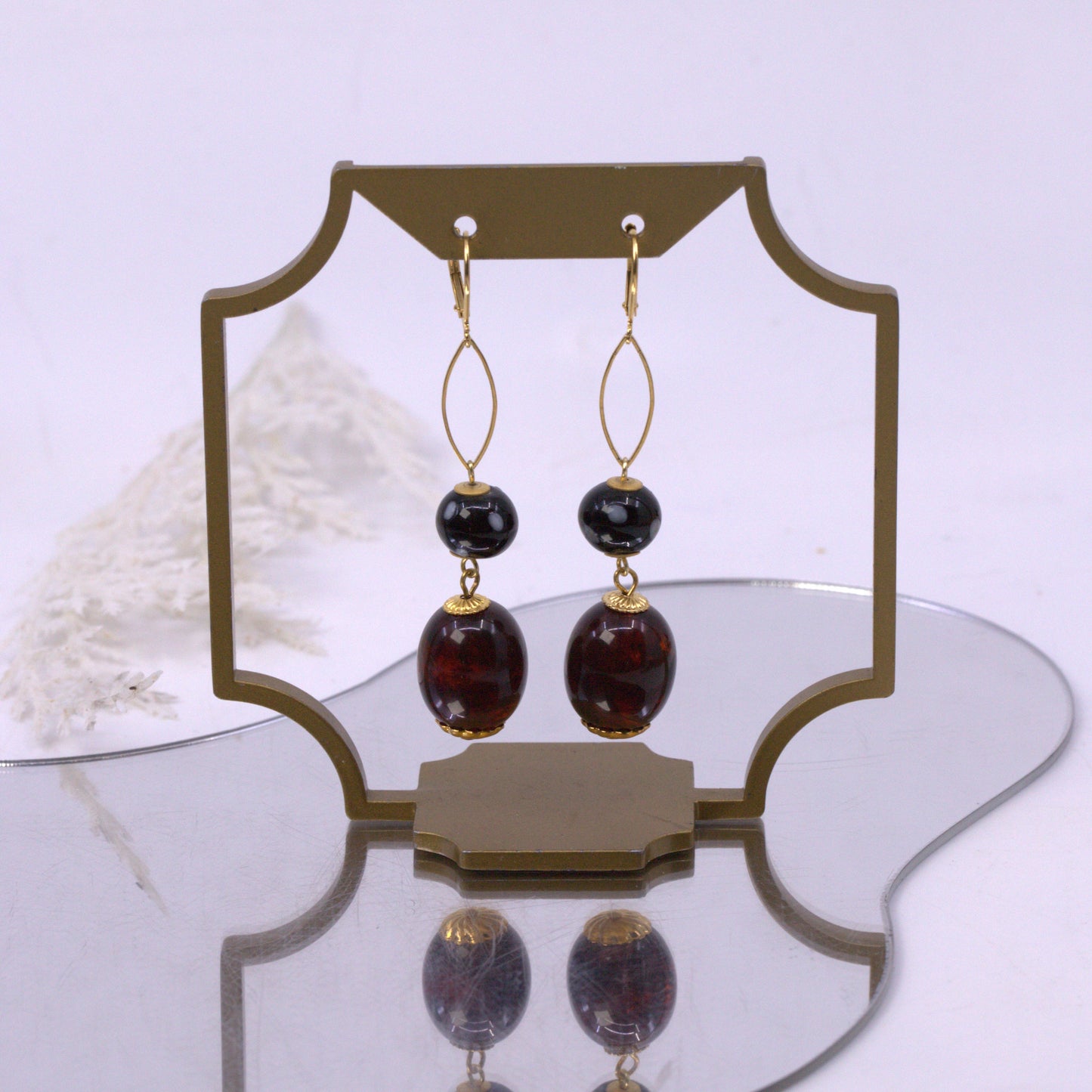 Pair of earrings with gold and brown stones on a white background