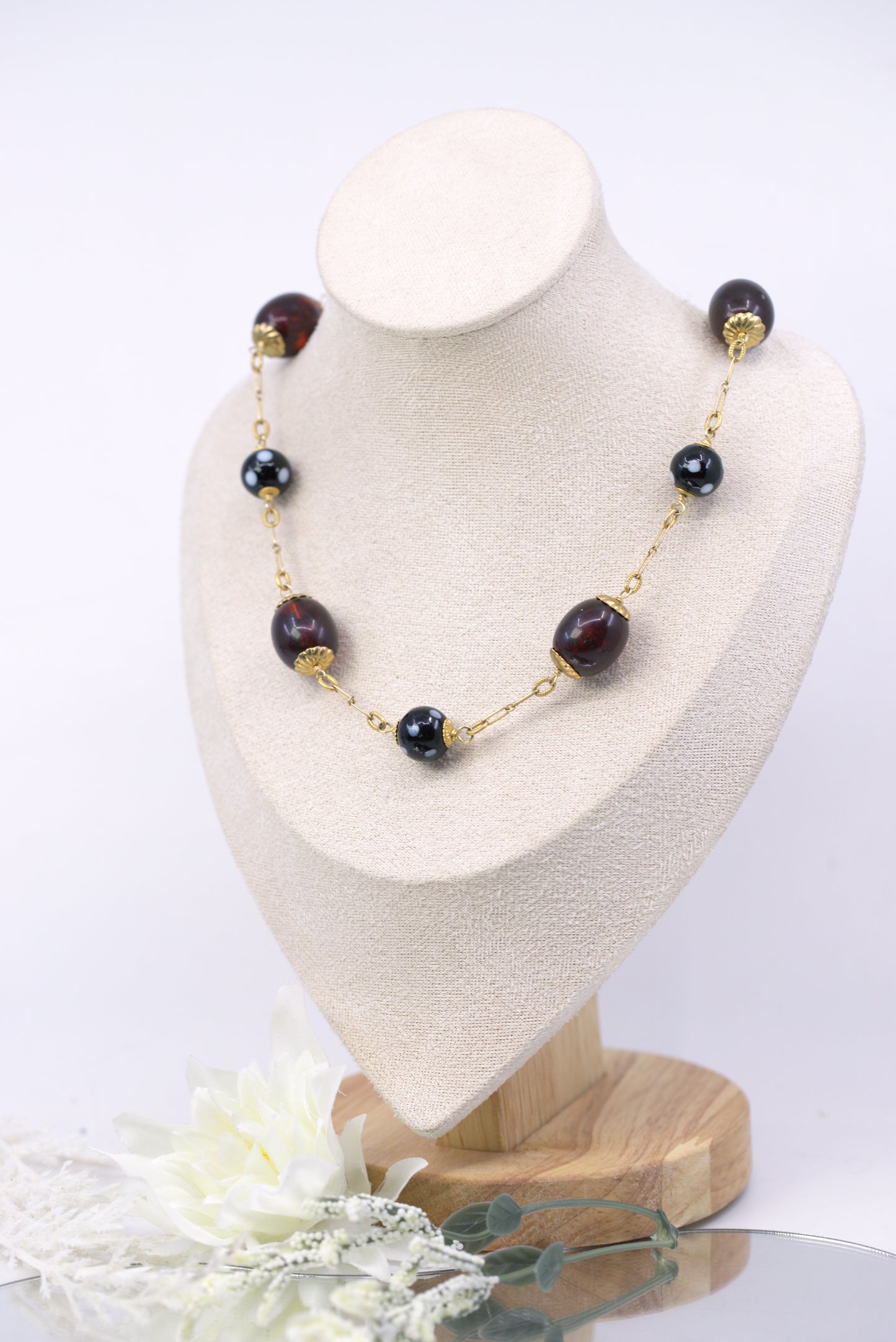 Necklace with black beads and gold accents on a white mannequin bust.