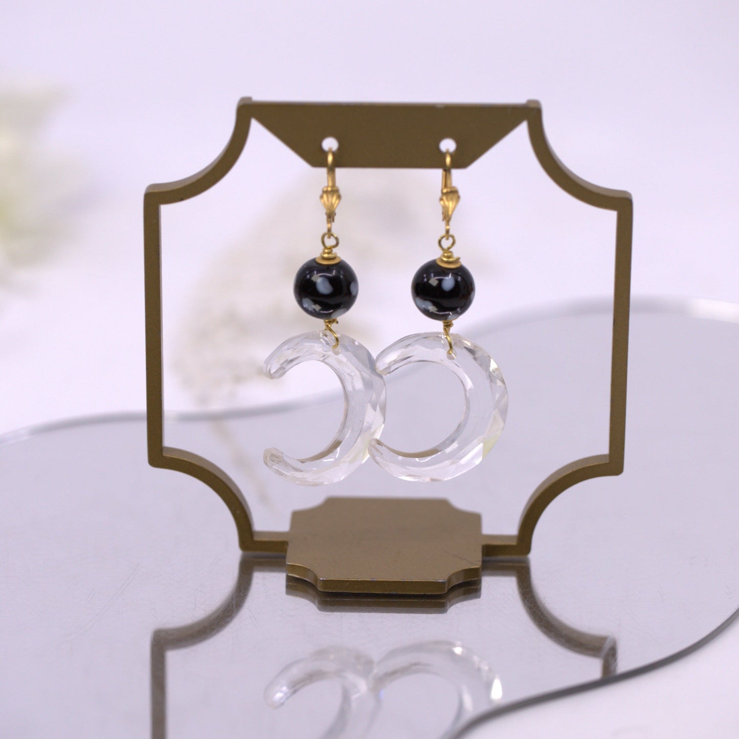 Pair of earrings on a decorative stand with a white background