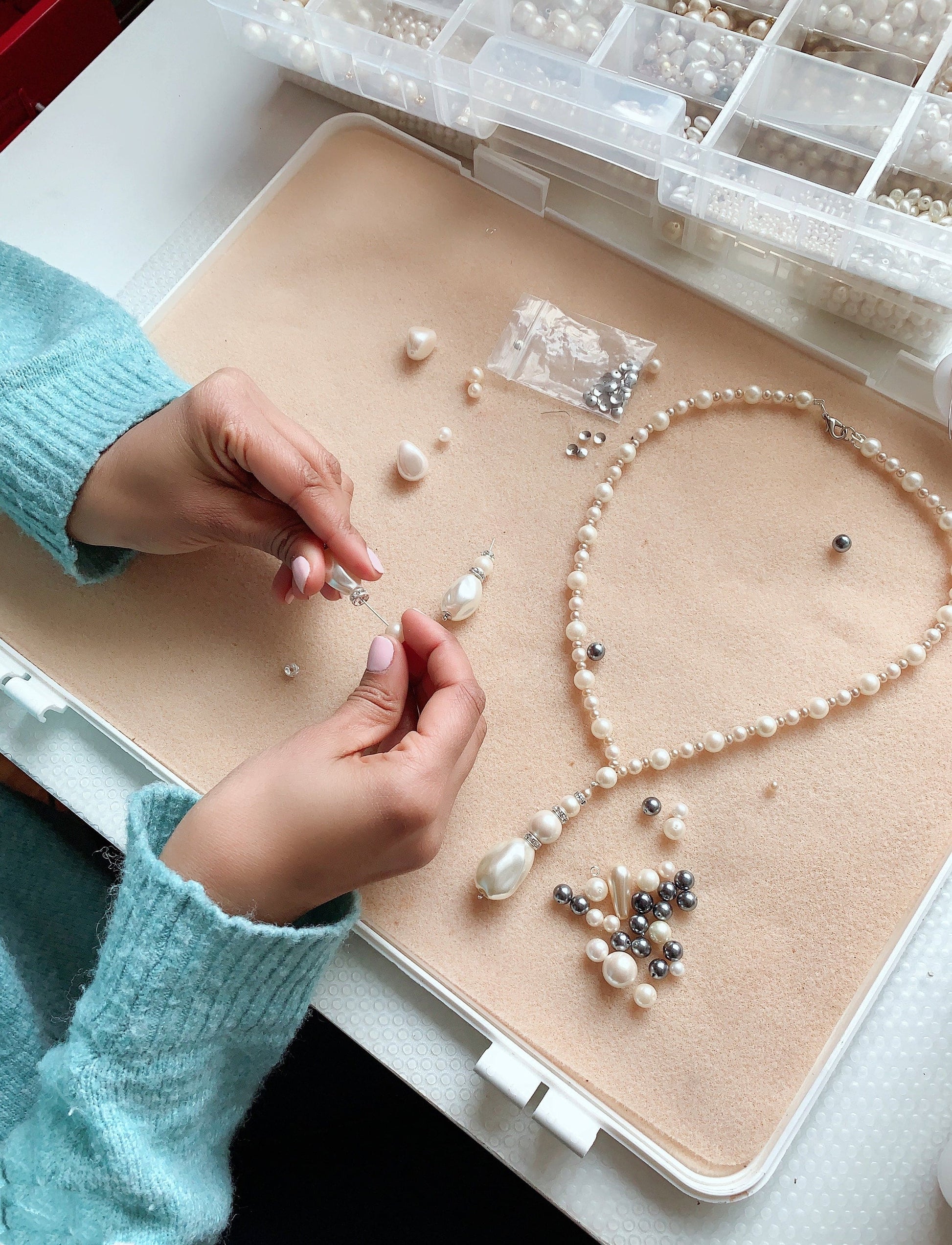 A bride carefully arranging bridal jewelry pieces on a velvet tray