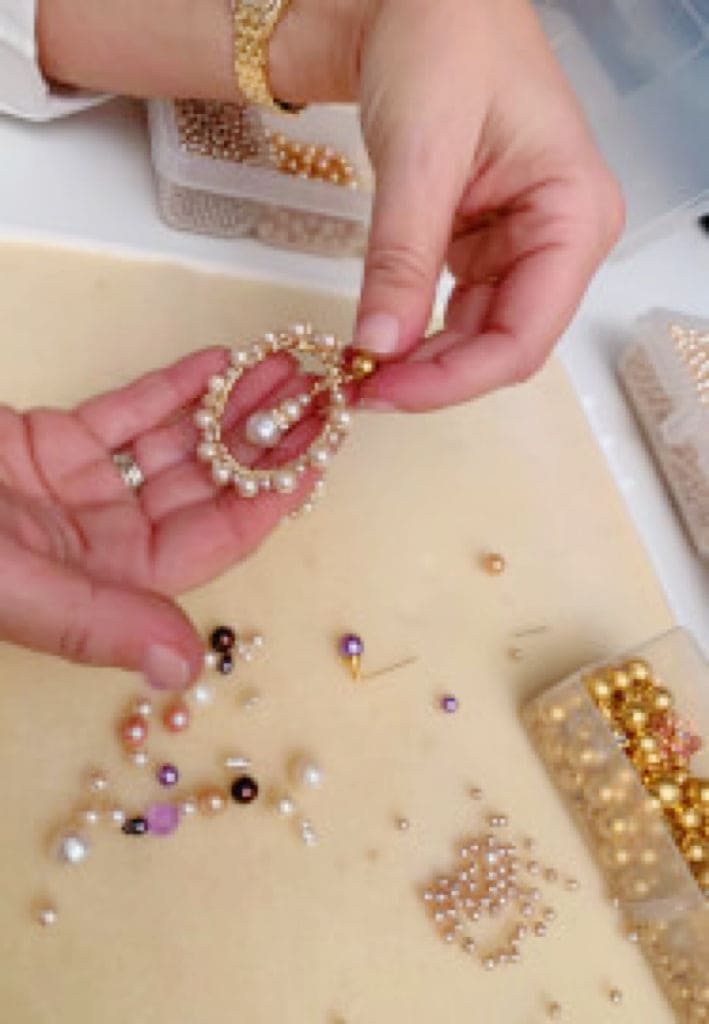 Close-up of hands assembling pearls and beads for a bridal bracelet