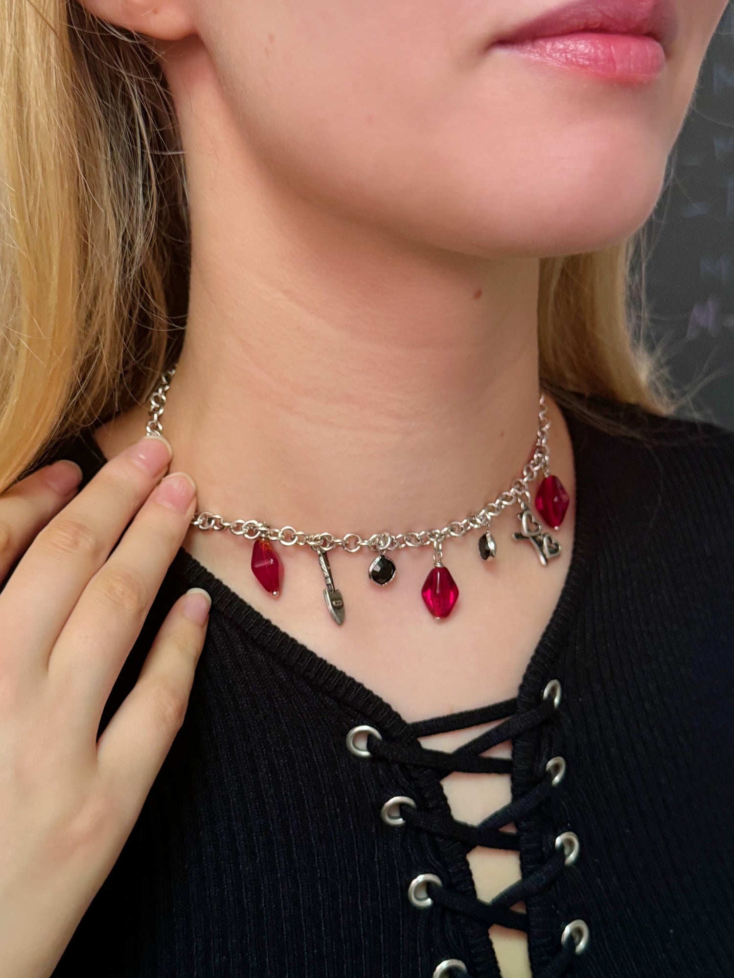 Close-up of a custom chain necklace with red and black charms, worn by a jewelry class participant after creating it in a NYC DIY workshop