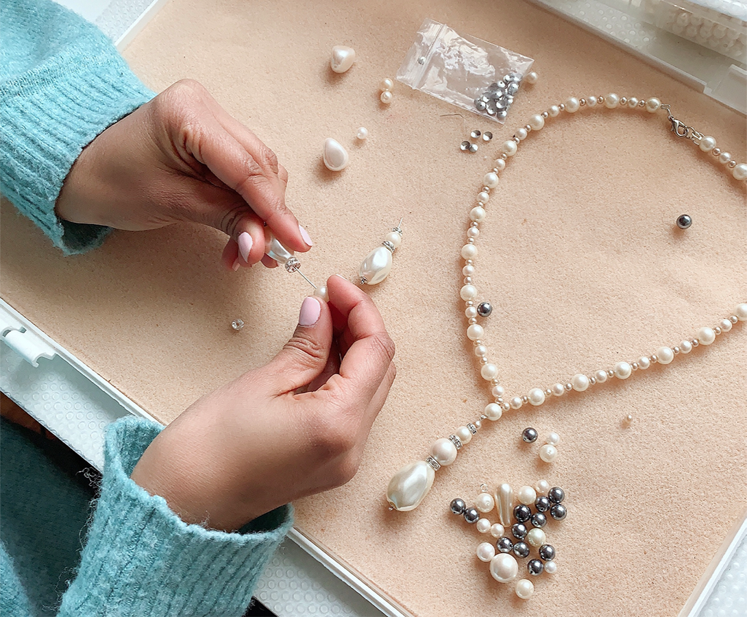 Close-up of hands arranging pearls and crystals for a custom jewelry design