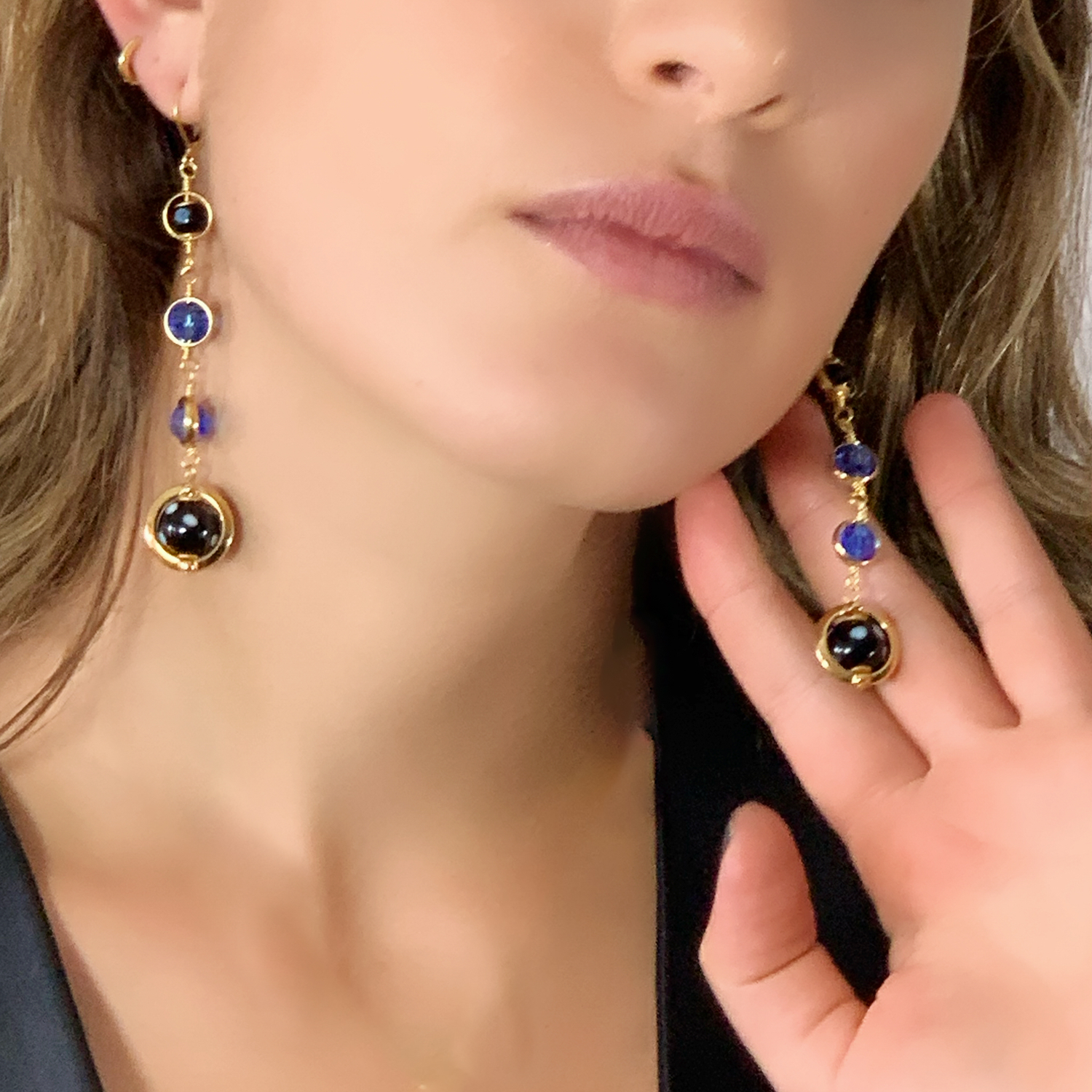 Model wearing long gold and blue Conta di Ojo evil eye earrings by Alzerina, inspired by Cape Verdean heritage for protection and style.