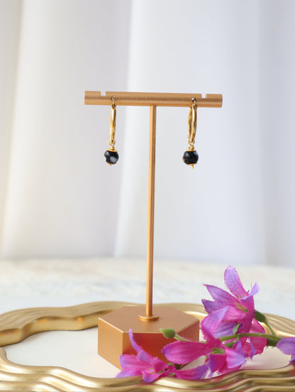 Gold kitchen faucet with a white wall and pink flowers in the background