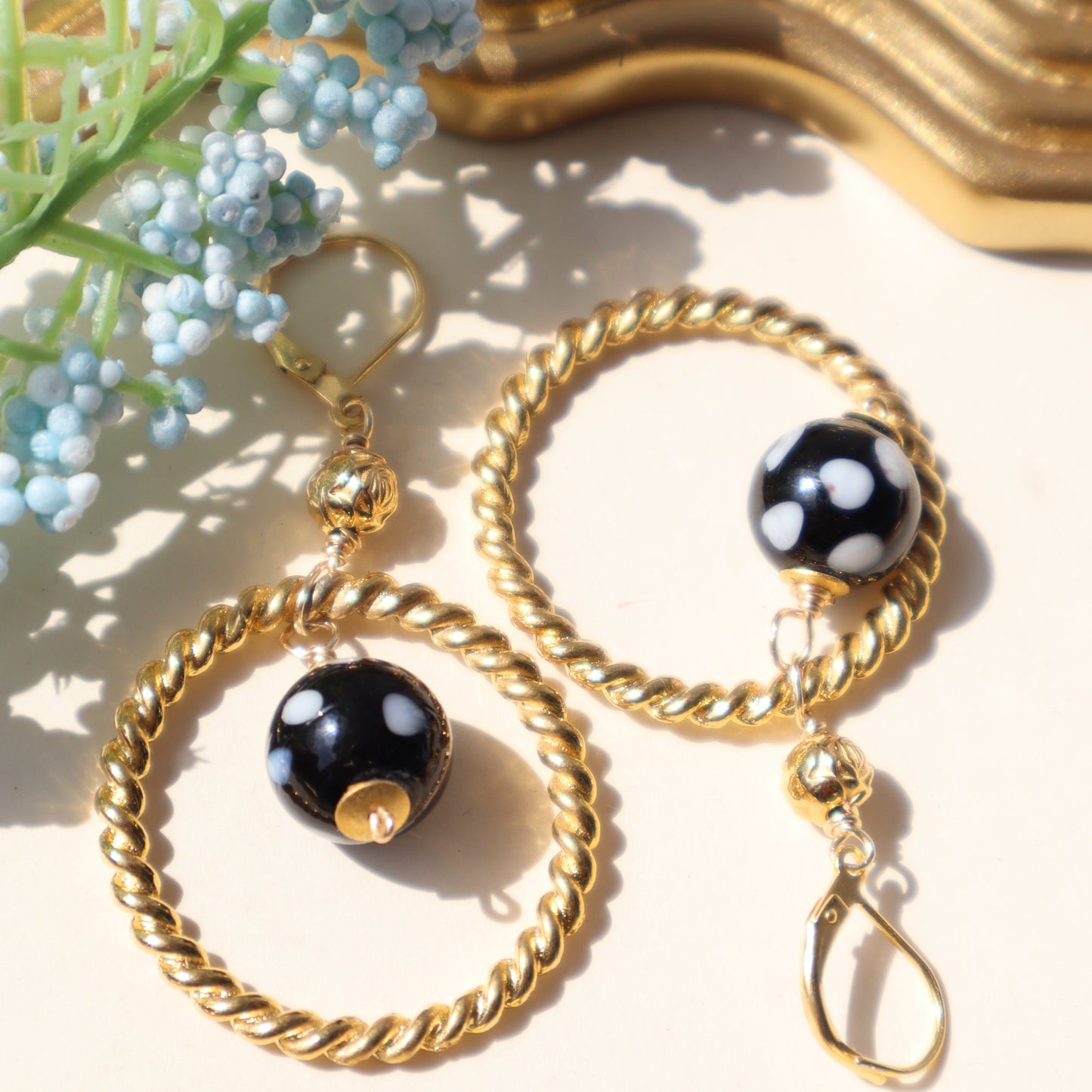 Gold hoop earrings with black beads on a light background