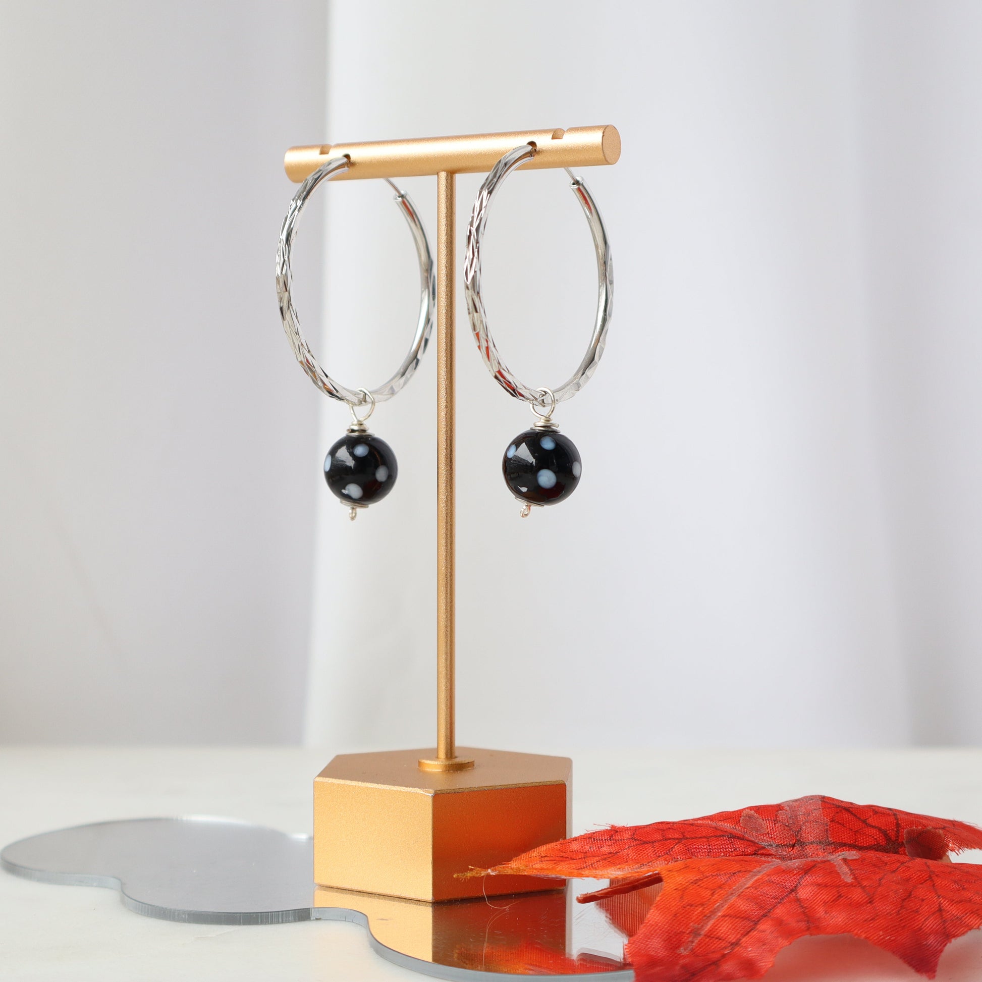Pair of hoop earrings with black beads on a gold stand against a white background
