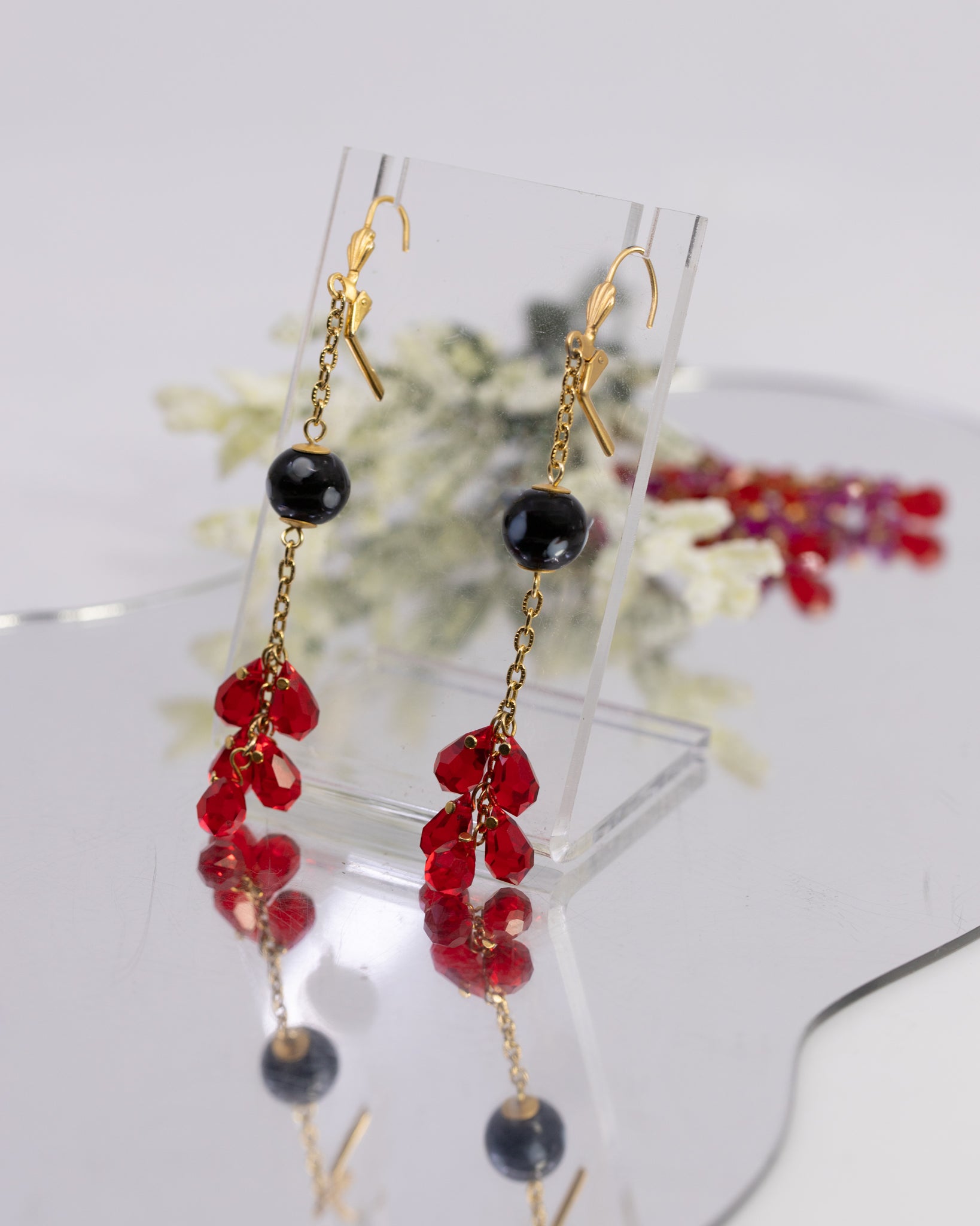 Pair of earrings with red and black beads on a white background