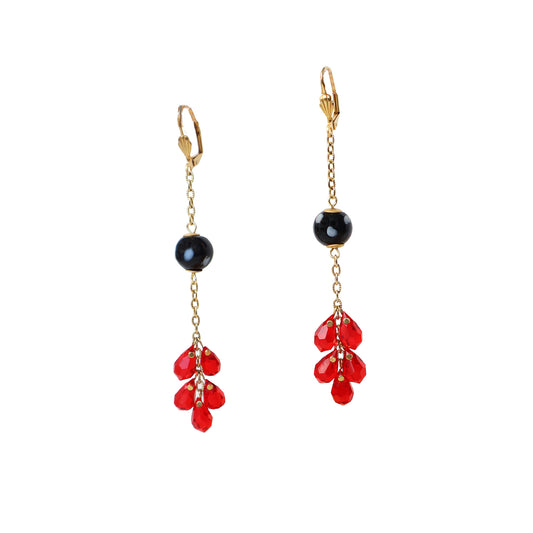 Gold earrings with black and red beads on a white background