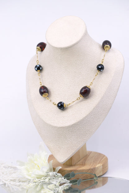 Necklace with black beads and gold accents on a white mannequin bust.