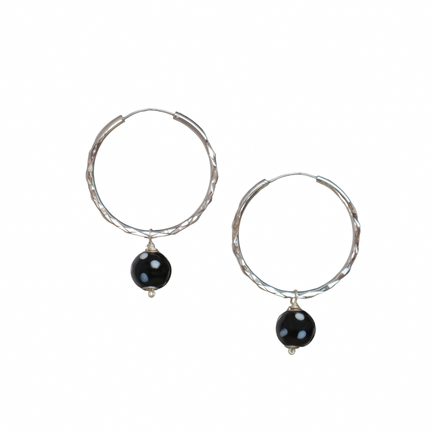 Silver hoop earrings with black evil eye charm, minimalist spiritual jewelry on white background.