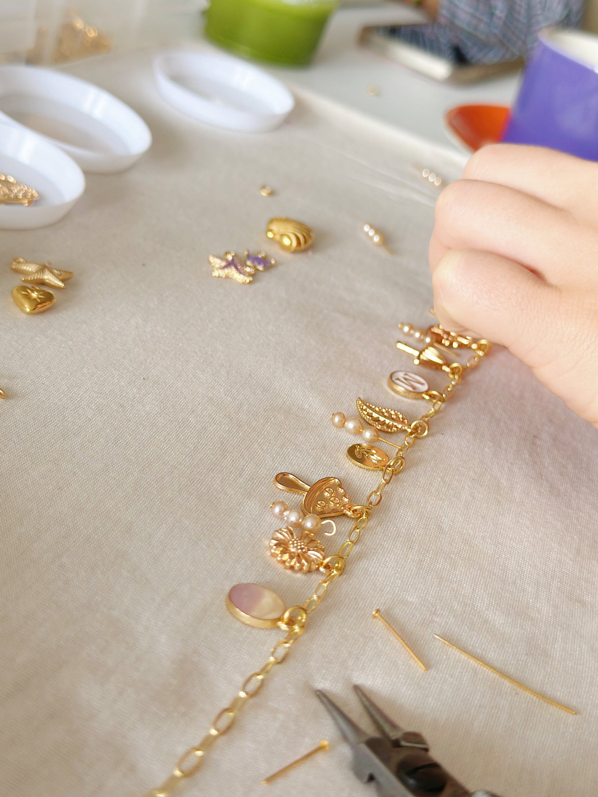 Close-up of stringing golden beads on the table
