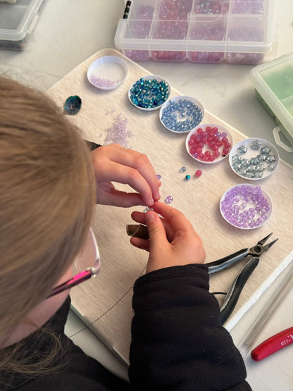Child organizing colorful beads in small containers during class
