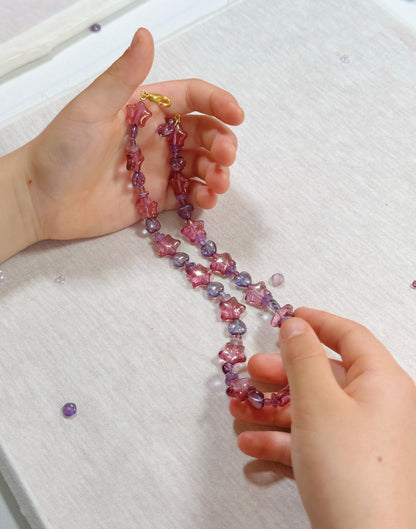 Child proudly holding up a completed bead necklace
