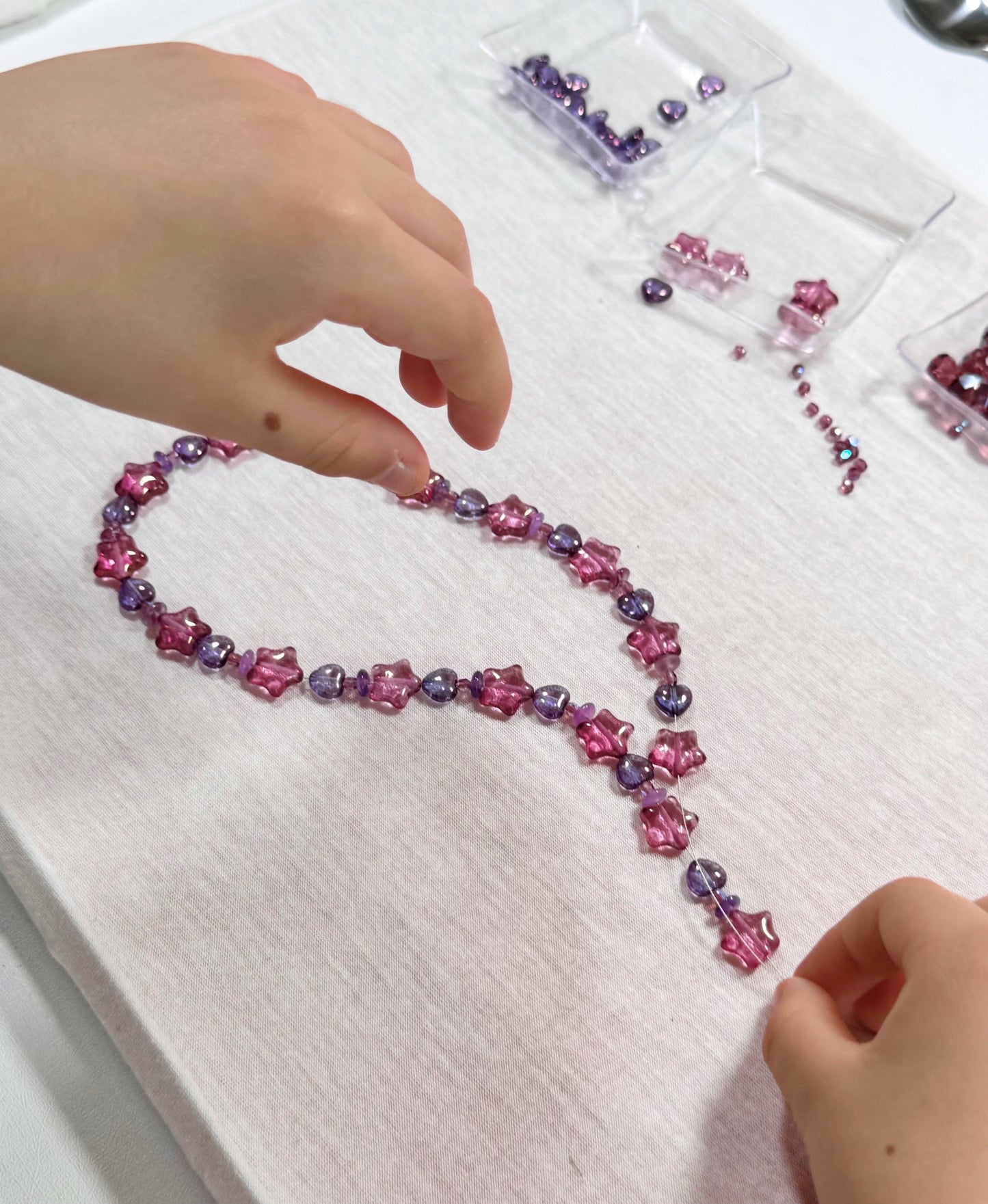 Child working on a pink bead necklace
