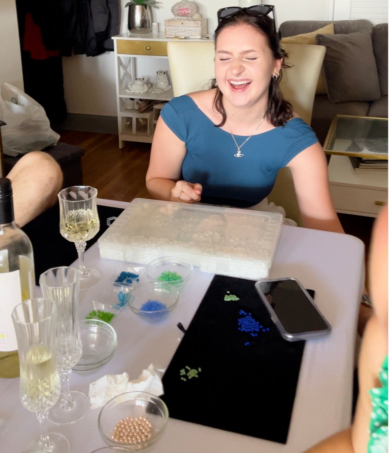 Group of girls laughing and making jewelry at a table
