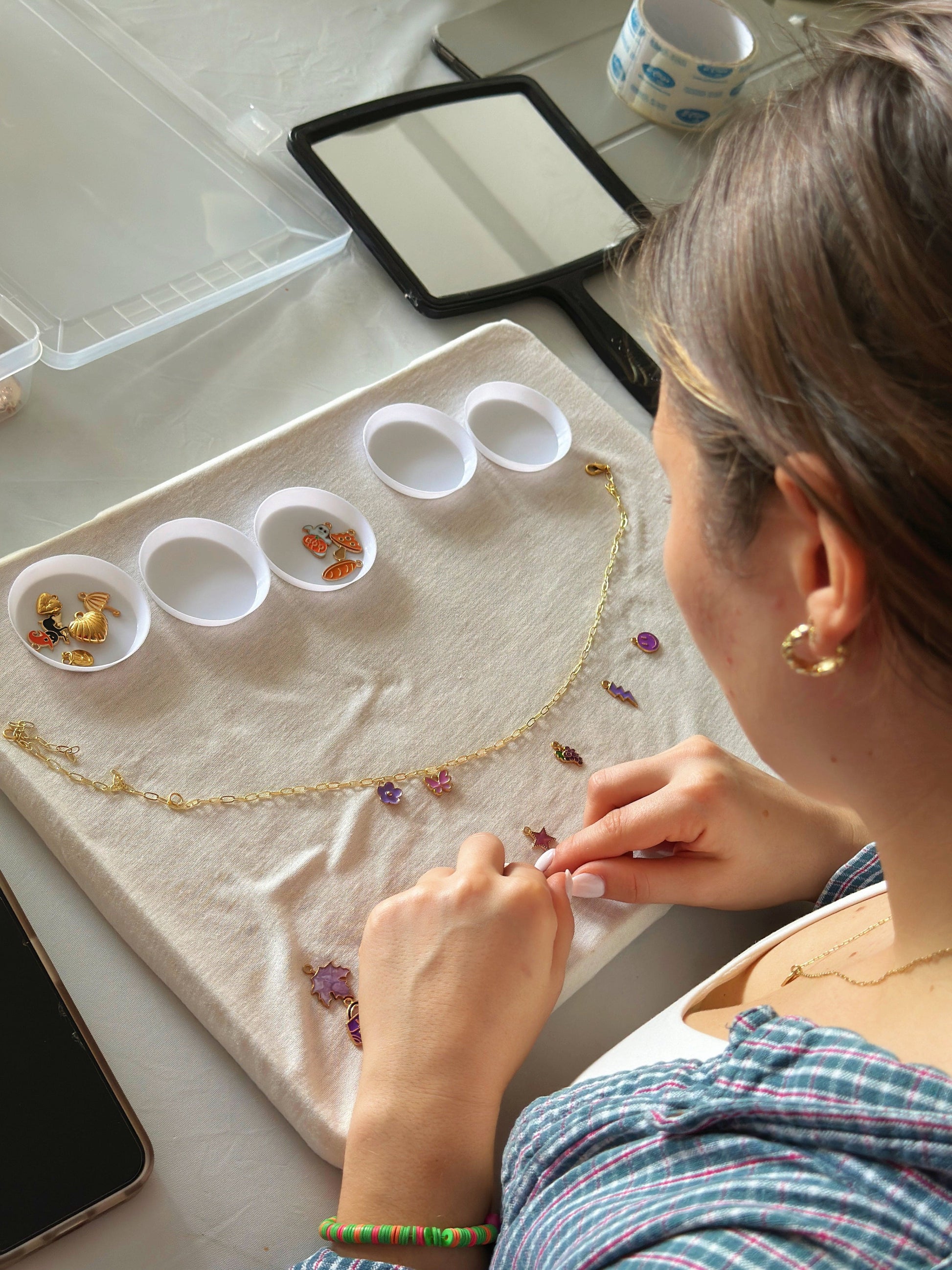Hands arranging small gems during jewelry class
