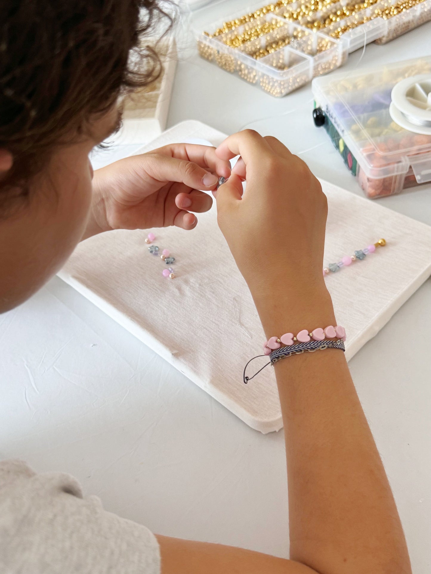 Child stringing purple and white beads for a DIY bracelet
