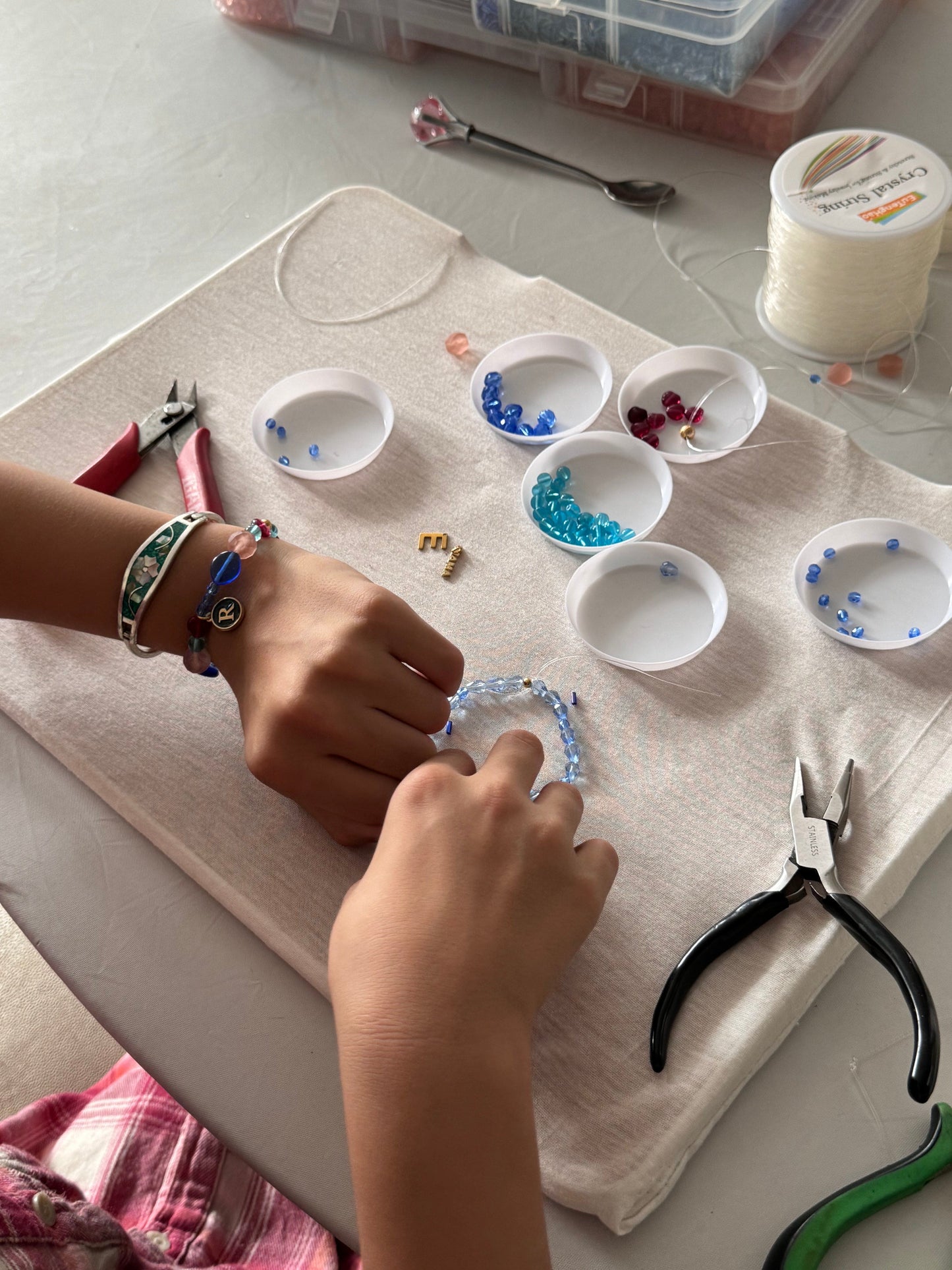 Children selecting beads and tools at the jewelry-making table
