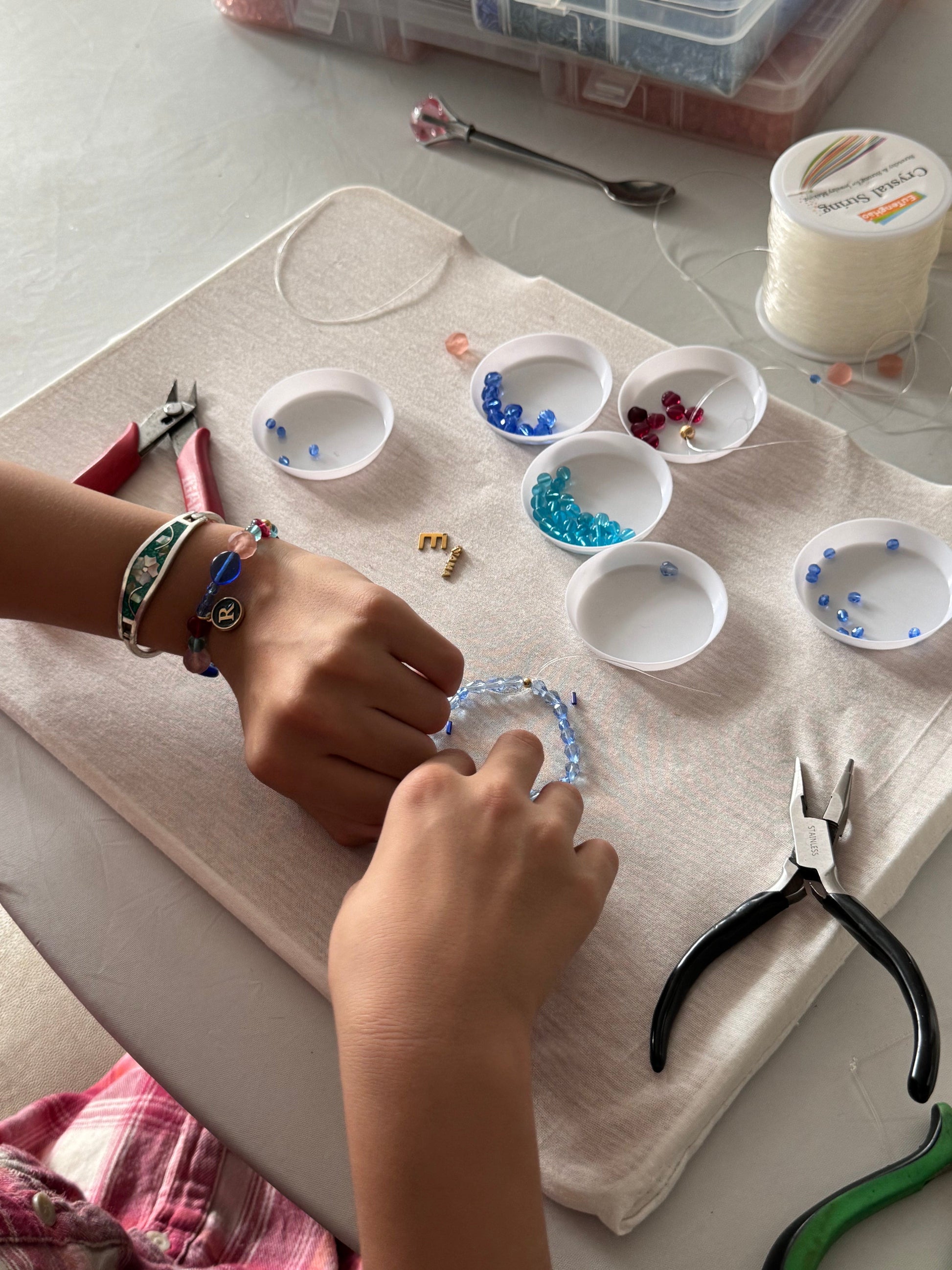 Children selecting beads and tools at the jewelry-making table
